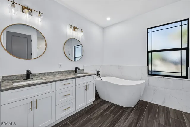 a bathroom with a double vanity sink mirror and bathtub