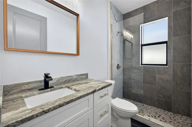 a bathroom with a sink a toilet a mirror and shower