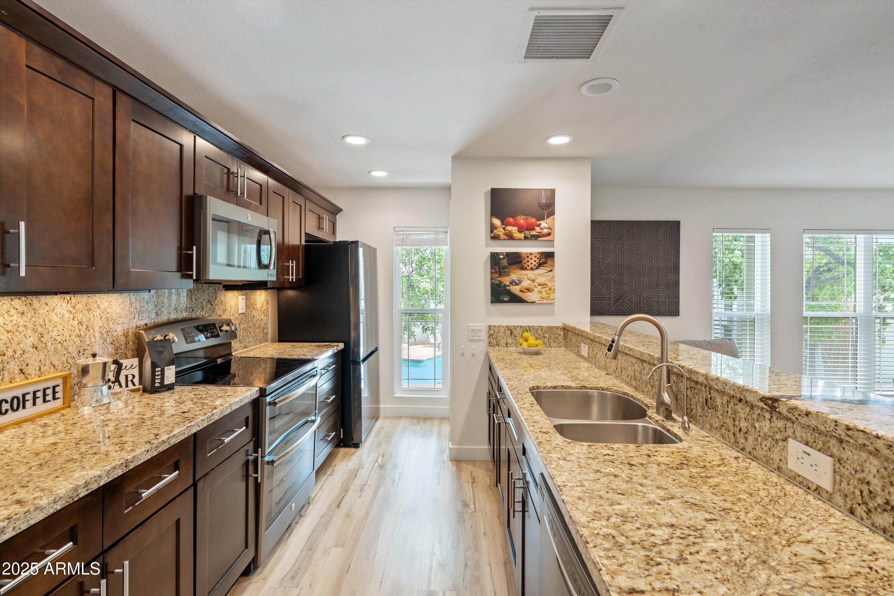 5201 North 24th Street, Unit 206 Phoenix, AZ 85016 - Photo 3 of 39 a kitchen with stainless steel appliances granite countertop sink stove refrigerator and cabinets