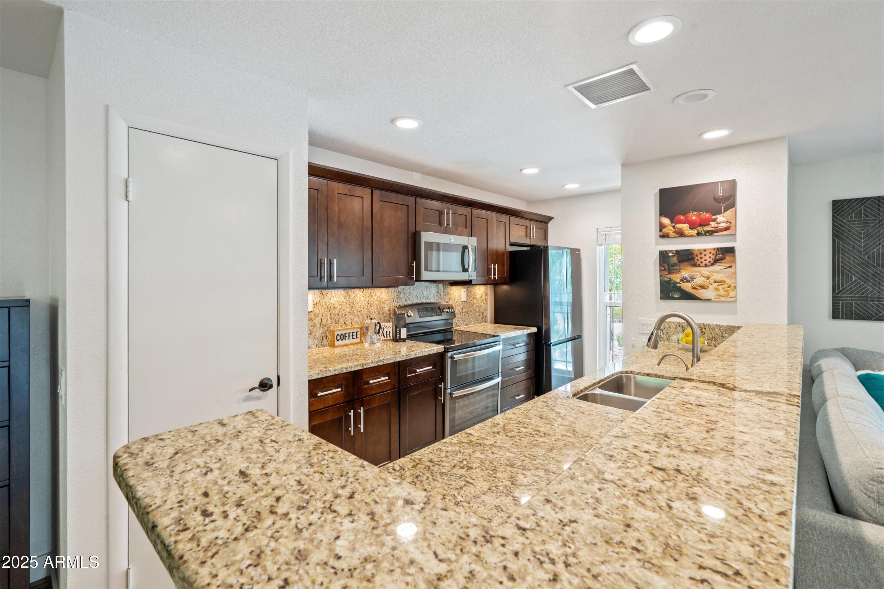 5201 North 24th Street, Unit 206 Phoenix, AZ 85016 - Photo 4 of 39 a kitchen with stainless steel appliances kitchen island granite countertop a refrigerator and a sink