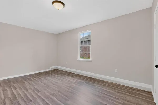 a view of empty room with window and wooden floor