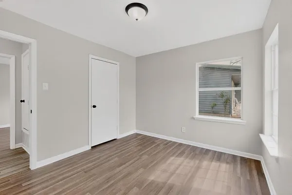 a view of an empty room with window and wooden floor