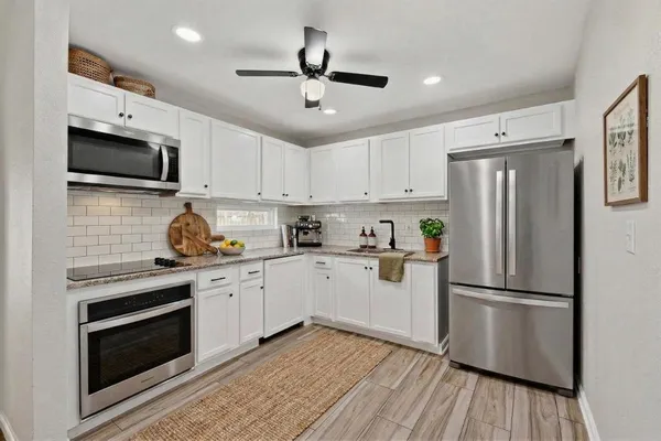 a kitchen with a sink stainless steel appliances and white cabinets