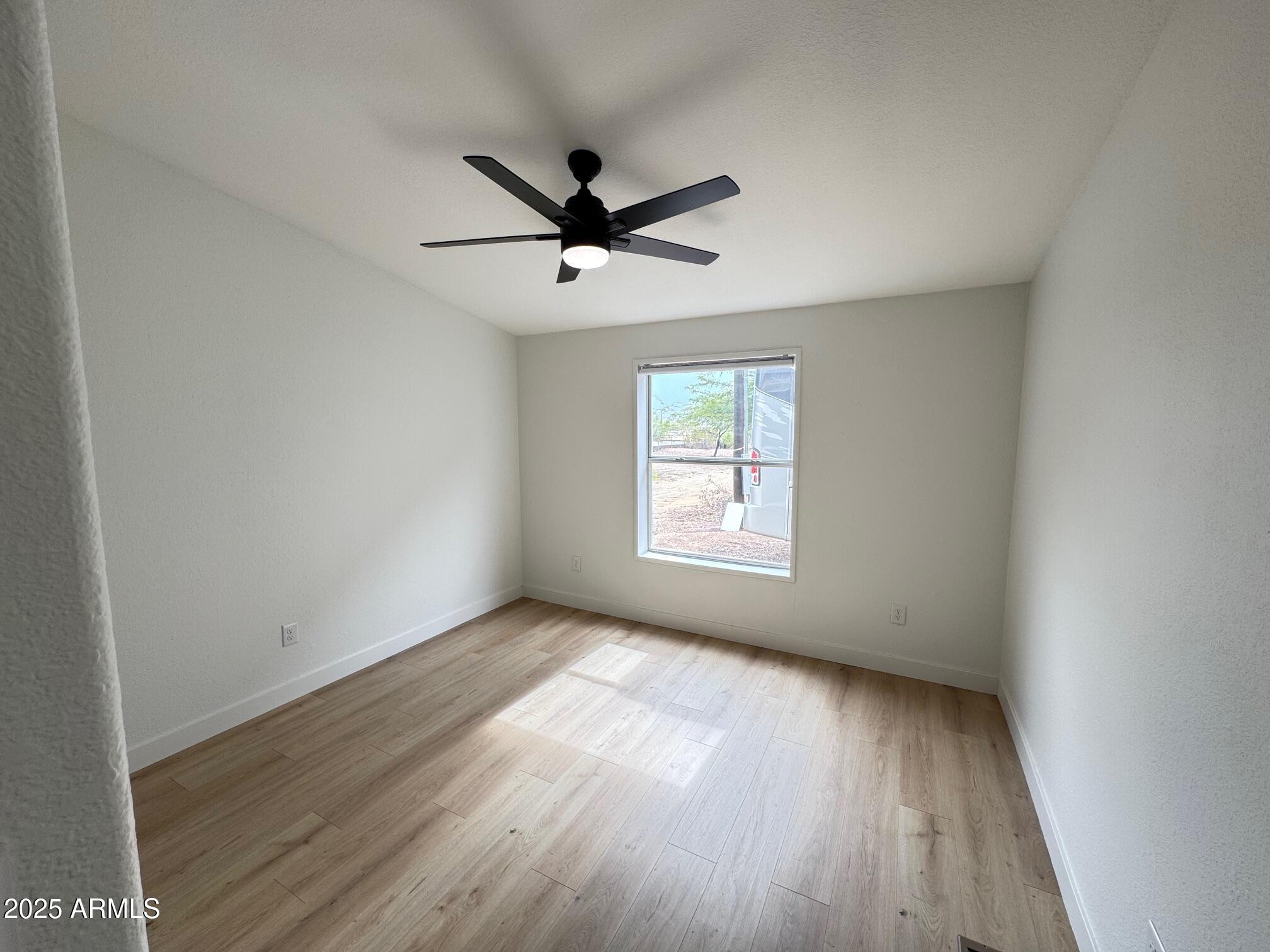 1835 East 20th Avenue Apache Junction, AZ 85119 - Photo 18 of 29 an empty room with wooden floor fan and windows