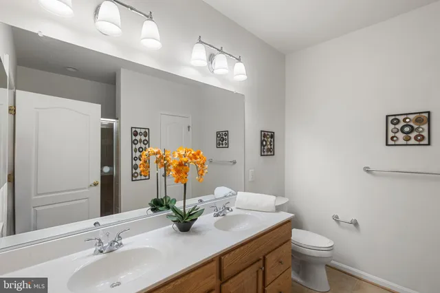 a bathroom with a granite countertop sink toilet and large mirror