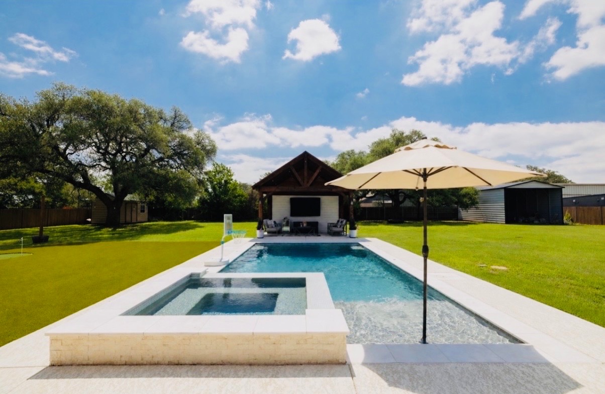 Rectangular swimming pool with integrated spa and surrounding light-toned coping