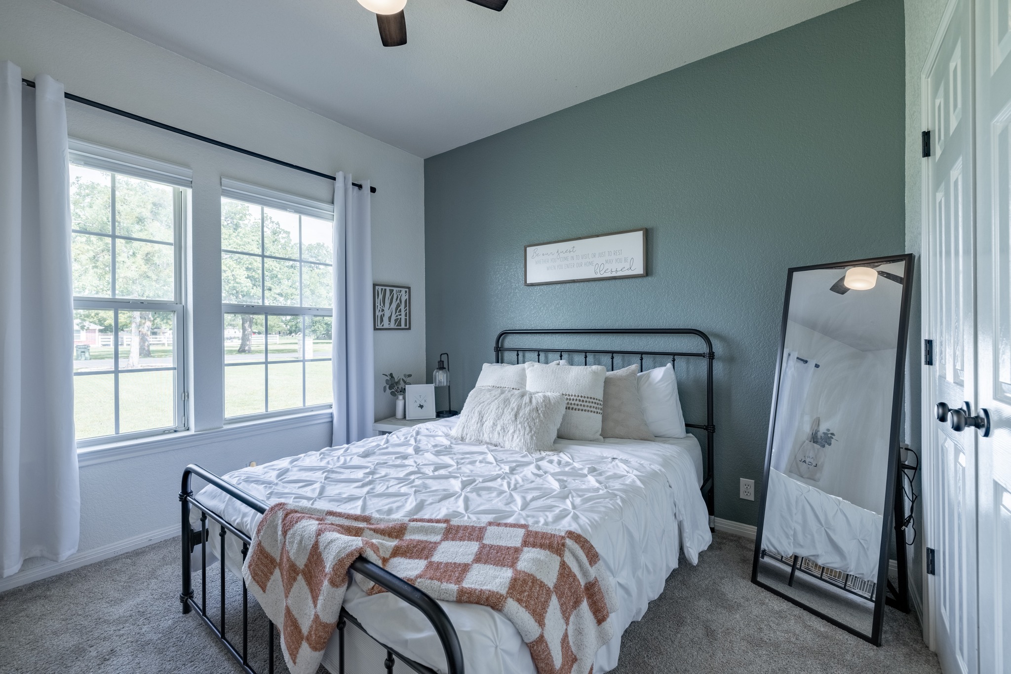 108 Kyle Lane Georgetown, TX 78633 - Photo 13 of 26 Bedroom featuring a ceiling fan, two double-hung windows with grilles, a textured accent wall, and carpet flooring