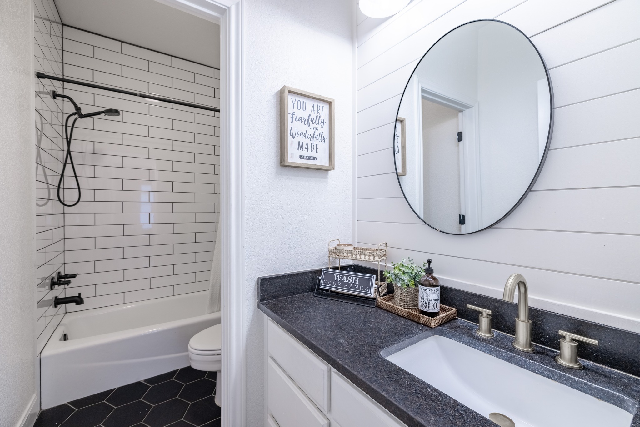 108 Kyle Lane Georgetown, TX 78633 - Photo 16 of 26 Bathroom featuring a white subway tile shower surround with black fixtures, a white bathtub, and black hexagonal floor tiles