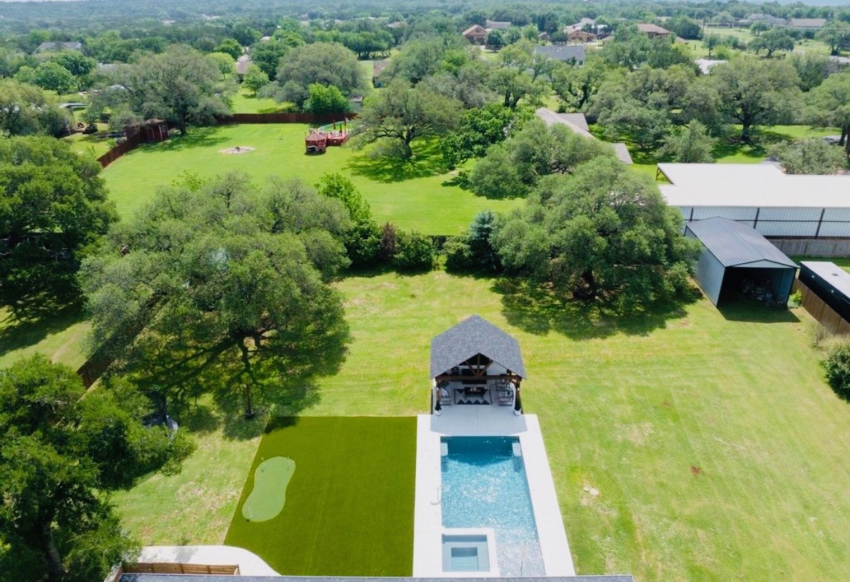 108 Kyle Lane Georgetown, TX 78633 - Photo 25 of 26 Backyard oasis featuring a rectangular swimming pool with integrated spa, adjacent covered outdoor kitchen, and artificial turf putting green