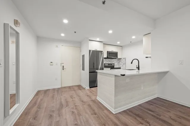 a view of a kitchen with sink stainless steel appliances and wooden floor