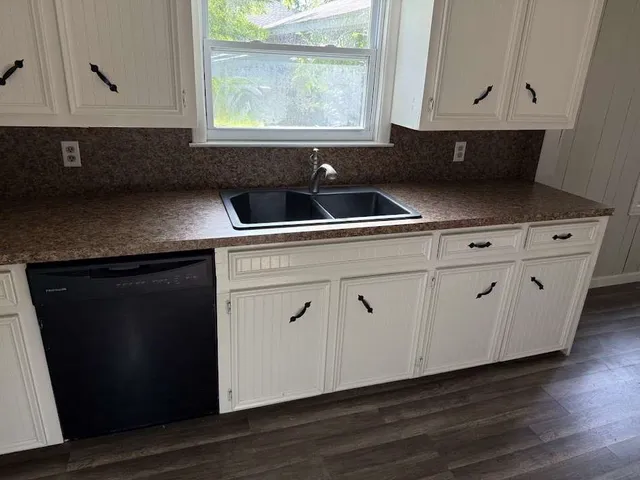 a kitchen with granite countertop white cabinets and black appliances