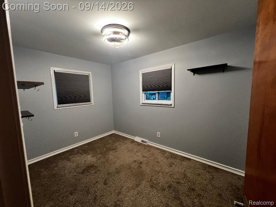 1615 Ladd Road Walled Lake, MI 48390 - Photo 19 of 28 Gray wall paint, two windows with blinds, brown carpet flooring, flush mount ceiling light fixture, white trim molding