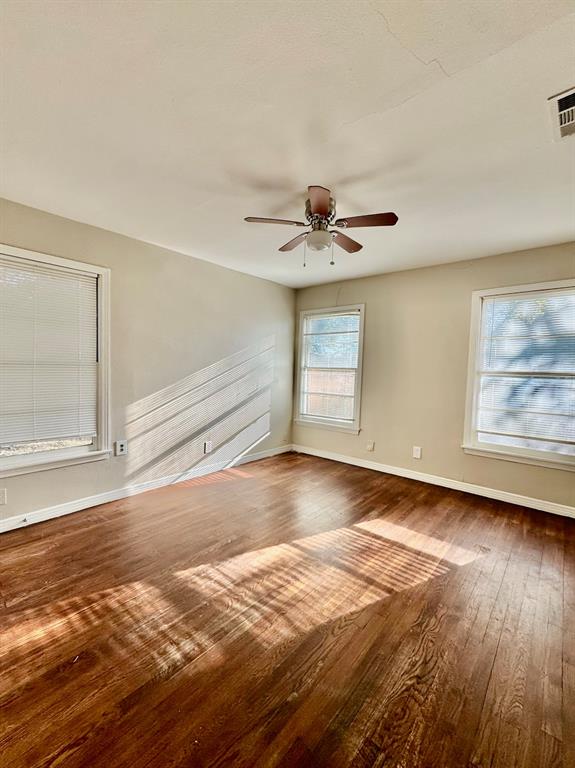 Spacious room featuring wood-finish flooring and multiple windows for natural light