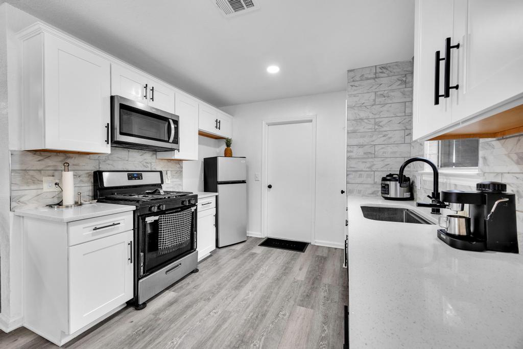 600 Smoke Signal Pass Pflugerville, TX 78660 - Photo 13 of 35 a kitchen with stainless steel appliances granite countertop a stove a sink dishwasher a microwave oven and a refrigerator with wooden floor
