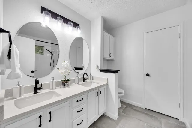a bathroom with a double vanity sink and mirror with toilet