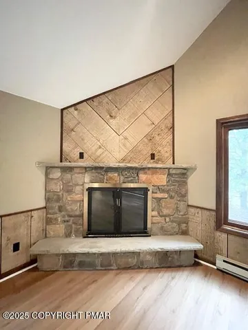 a living room with a fireplace furniture a ceiling fan and a wooden floor