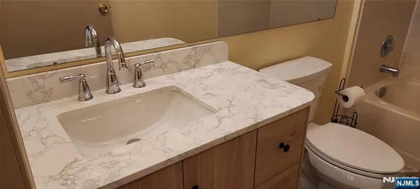 a bathroom with a granite countertop sink a toilet and mirror