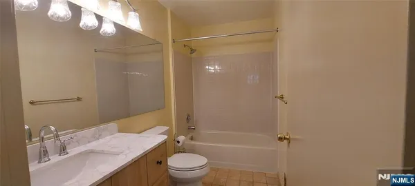 a bathroom with a granite countertop bathtub shower sink vanity and toilet