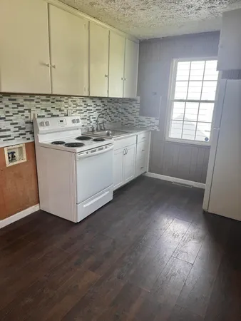 a kitchen with stainless steel appliances granite countertop a sink a stove a refrigerator and wooden floor