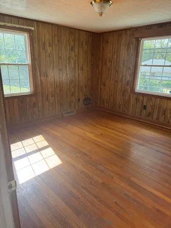 an empty room with wooden floor and windows