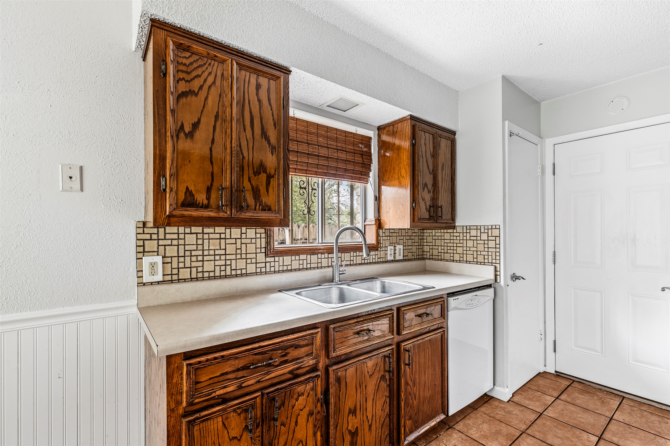 7506 Glenhill Road Austin, TX 78752 - Photo 7 of 24 A functional kitchen features rich wood cabinetry and a classic tile backsplash, ready for daily meals.