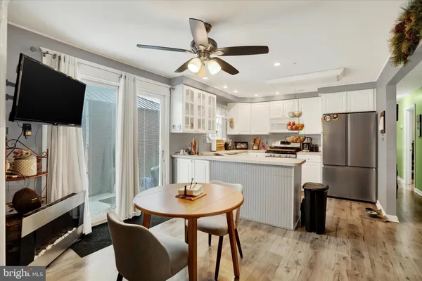 a kitchen with stainless steel appliances a dining table chairs refrigerator and microwave