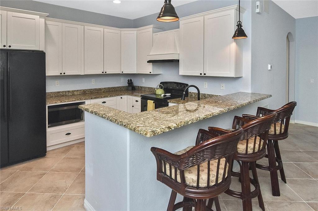 8949 Malibu Street, Unit 303 Naples, FL 34113 - Photo 27 of 50 a kitchen with granite countertop a table chairs stove and cabinets