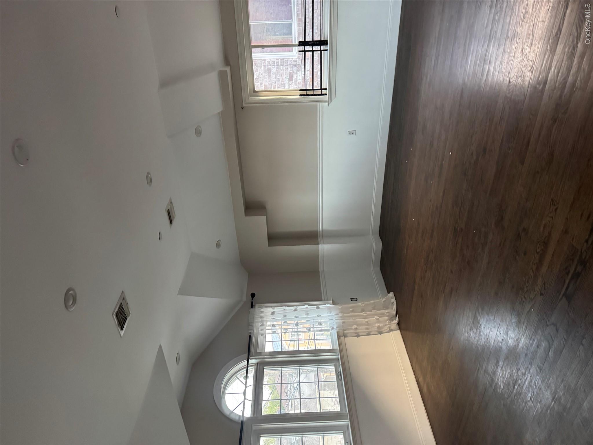 13916 Caney Lane, Unit 2 Queens, NY 11422 - Photo 2 of 9 an empty room with wooden floor and windows