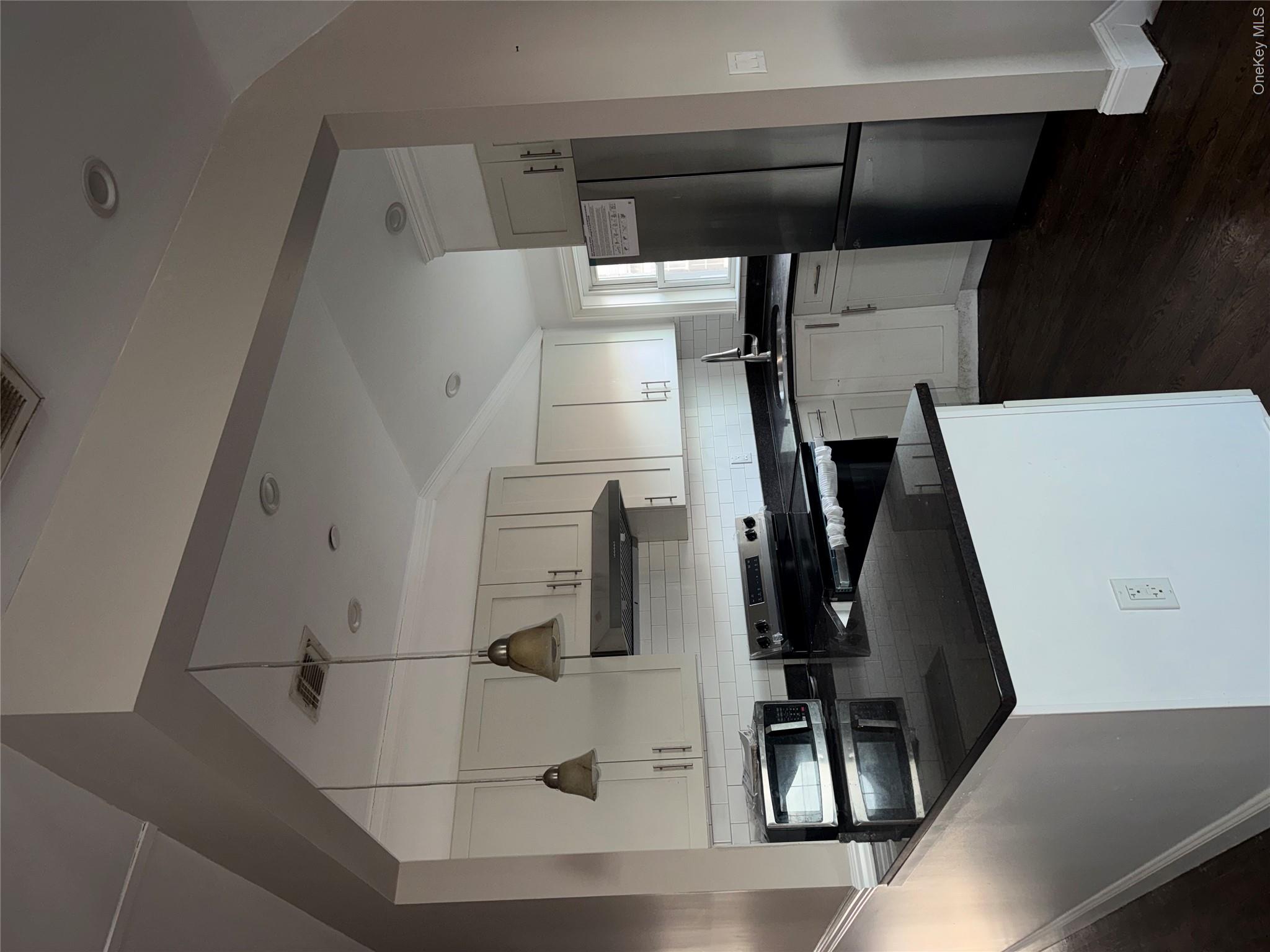 13916 Caney Lane, Unit 2 Queens, NY 11422 - Photo 4 of 9 a kitchen with a sink a refrigerator and white cabinets