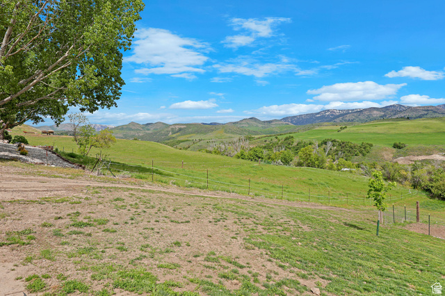 306 Spring Road Preston, ID 83263 - Photo 44 of 55 Expansive green landscape featuring rolling hills, distant mountains, and scattered trees under a blue sky