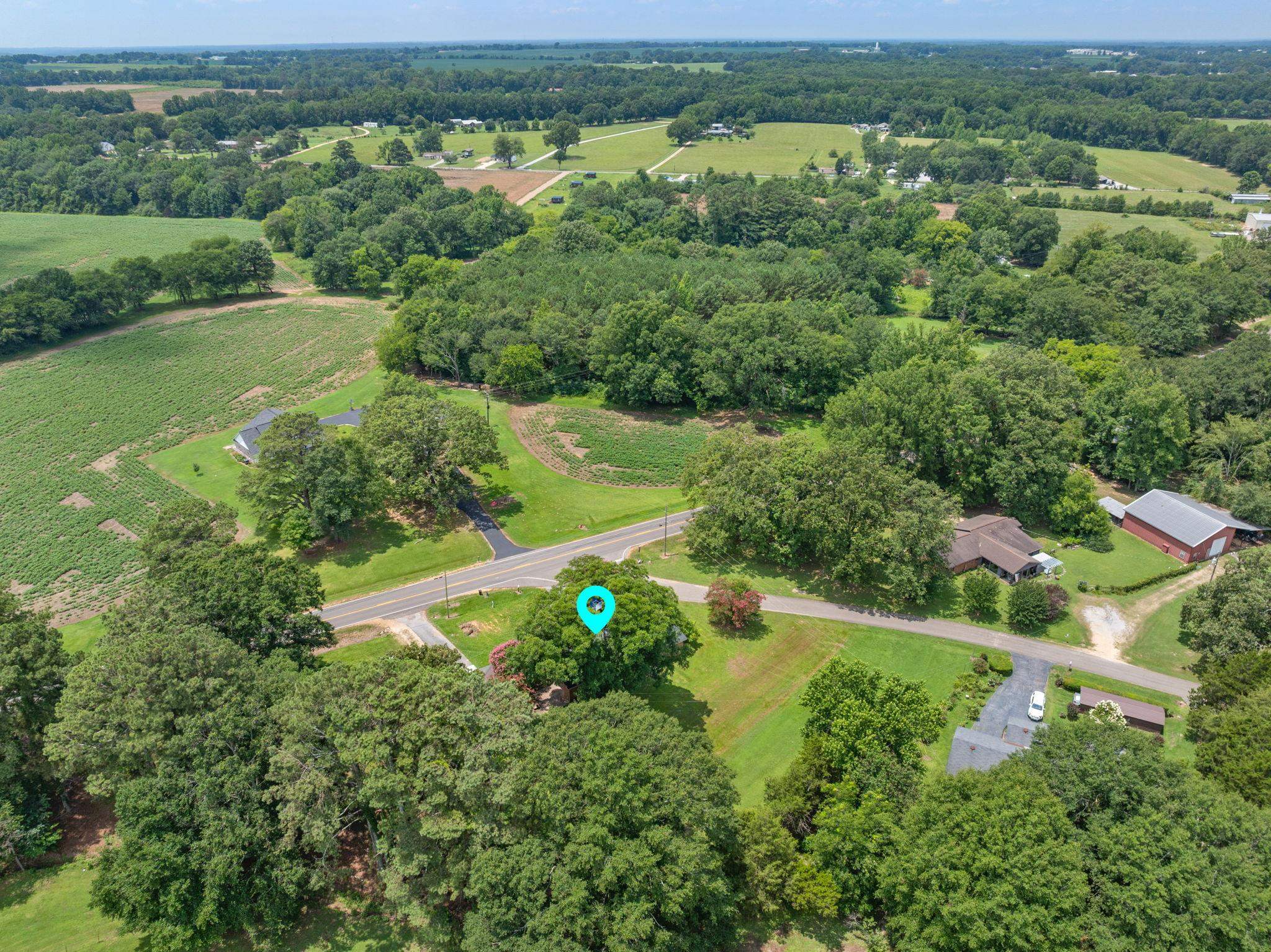 217 Red Bay Road Golden, MS 38847 - Photo 29 of 33 Expansive land parcel featuring a residential structure, mature trees, open fields, paved road frontage, and a barn