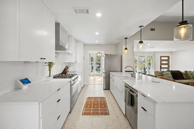 a large white kitchen with stainless steel appliances lots of counter space and wooden floor