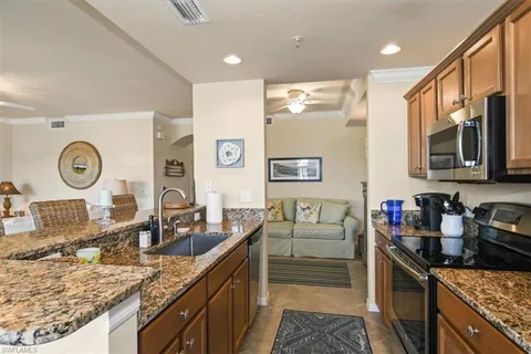 a kitchen with granite countertop a sink a stove top oven and refrigerator