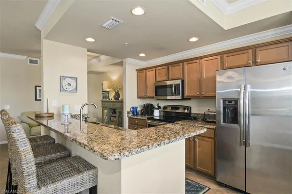 a kitchen with granite countertop kitchen island stainless steel appliances a refrigerator sink stove microwave and cabinets