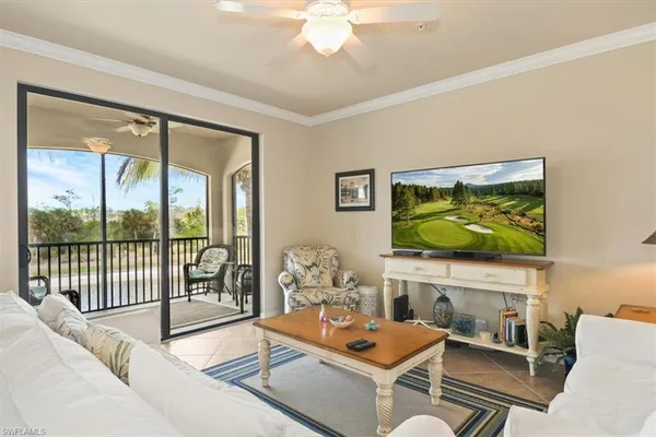 a living room with furniture a flat screen tv and floor to ceiling window