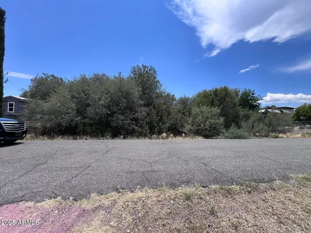 a view of dirt yard with a car parked on the road