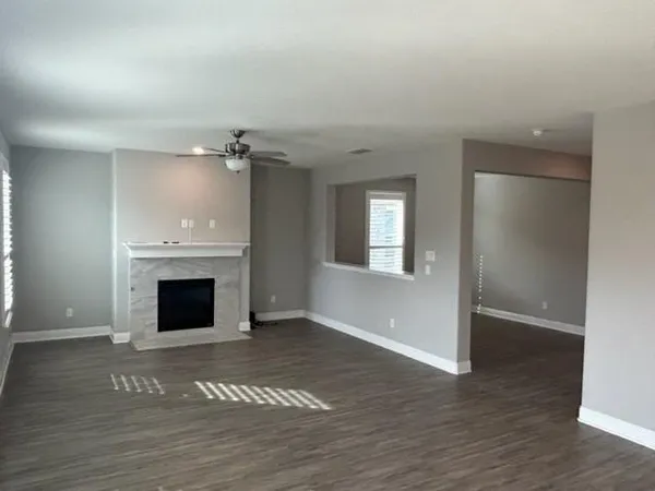 an empty room with wooden floor fireplace and windows