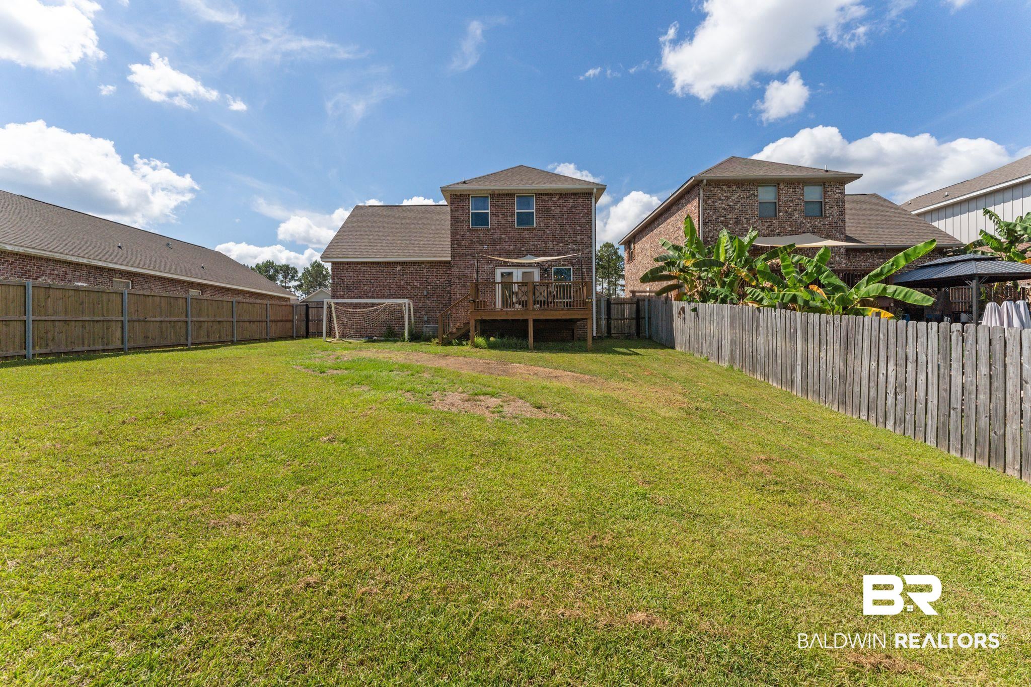 12711 Chickadee Lane Daphne, AL 36527 - Photo 32 of 39 Rear view of property featuring a wooden deck, brick siding, and a fenced backyard