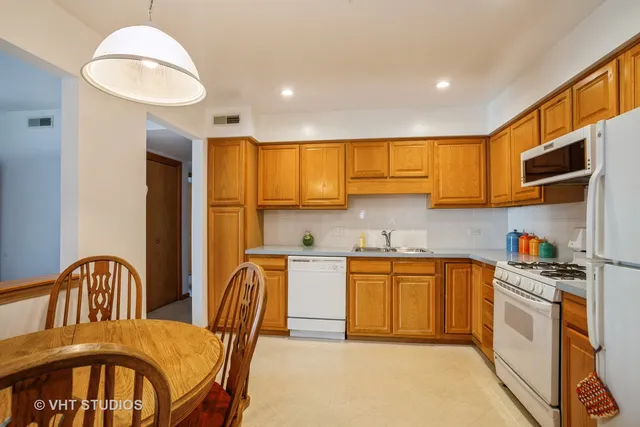 a kitchen with stainless steel appliances granite countertop a stove a sink dishwasher a dining table and chairs with wooden floor