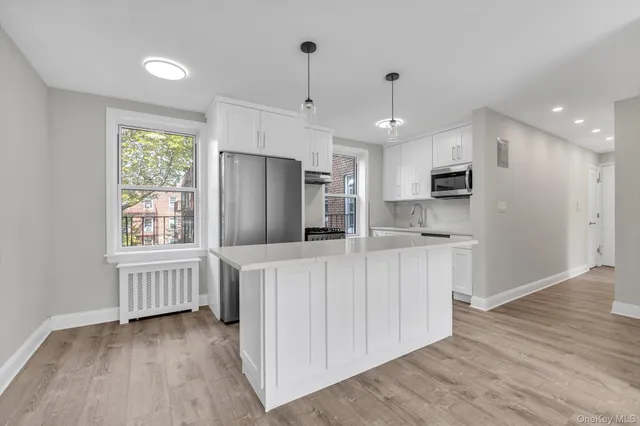 a kitchen with kitchen island wooden floors appliances cabinets and a center island