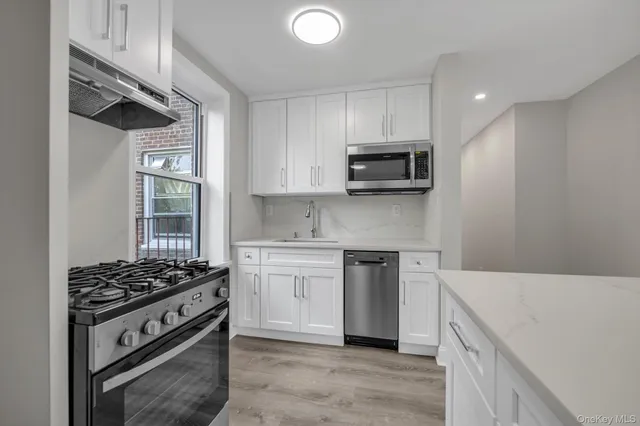 a kitchen with stainless steel appliances a stove a sink and a microwave