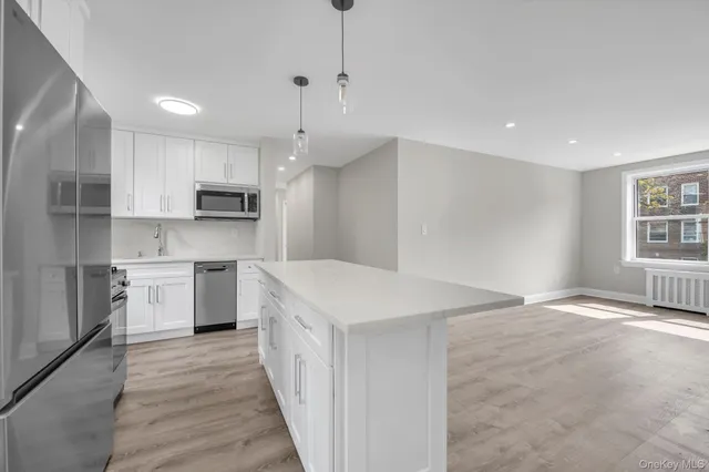 a kitchen with kitchen island a sink stainless steel appliances and white cabinets