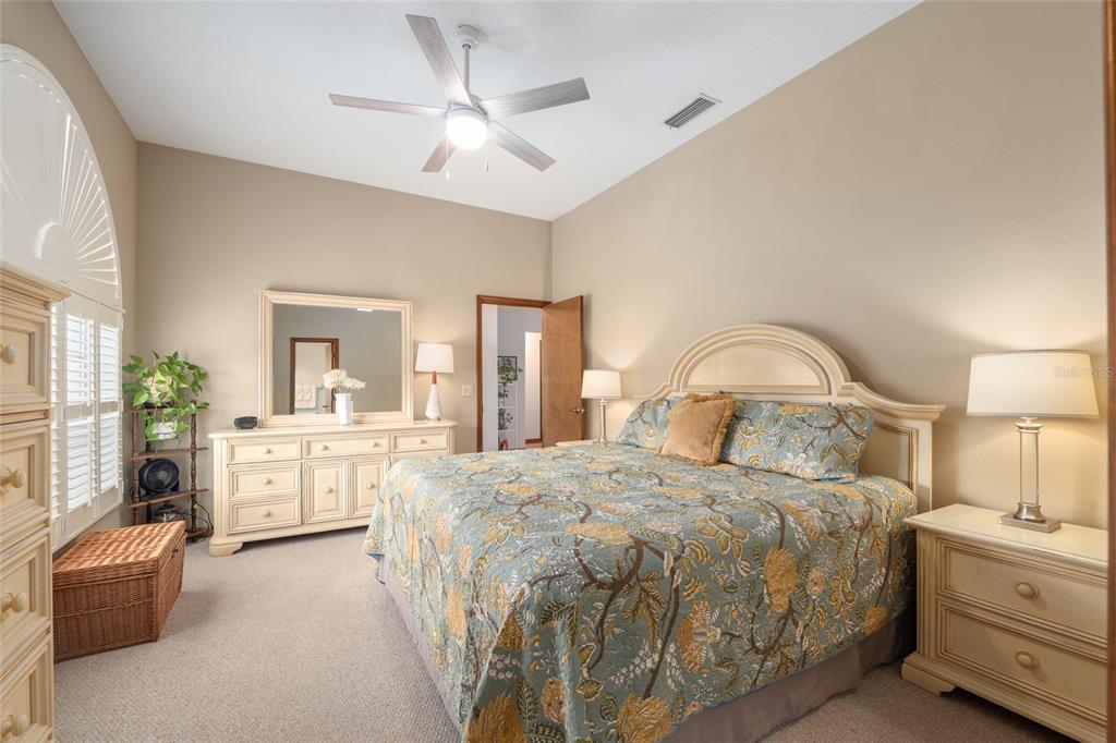 12094 Southeast 60th Avenue Road Belleview, FL 34420 - Photo 29 of 74 a spacious bedroom with a large bed and a chandelier