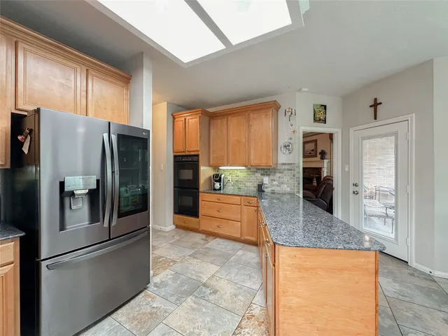 a large kitchen with stainless steel appliances kitchen island granite countertop a refrigerator and cabinets
