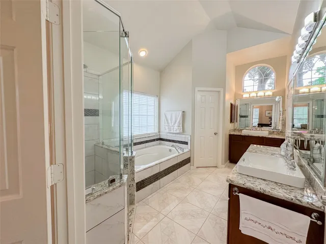 a spacious bathroom with a granite countertop tub mirror and shower