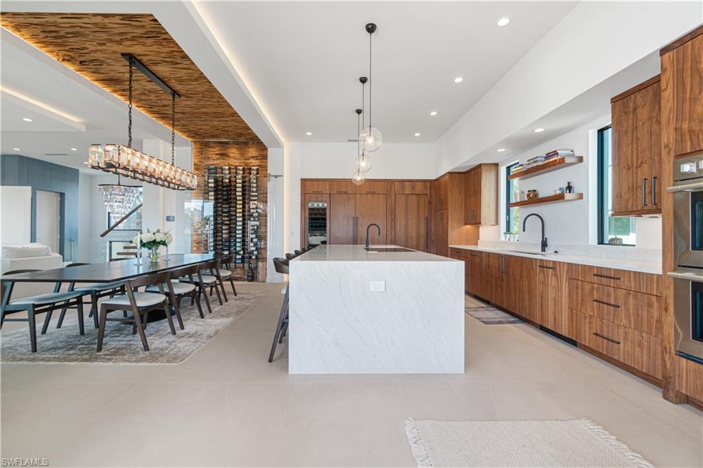 448 Oak Avenue Naples, FL 34108 - Photo 21 of 49 Kitchen with plenty of natural light, stainless steel oven, wall chimney range hood, light tile patterned floors, and an island with sink