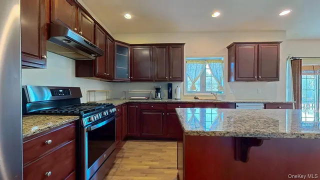 a kitchen with kitchen island granite countertop a sink stainless steel appliances and cabinets
