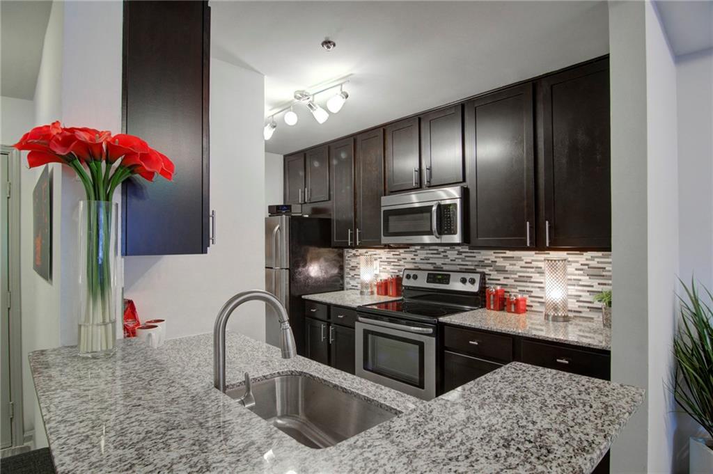 a kitchen with stainless steel appliances kitchen island granite countertop a stove a sink and a refrigerator