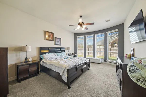 a spacious bedroom with a bed a table and large flat screen tv