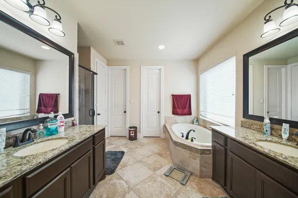 a bathroom with a granite countertop tub sink and mirror